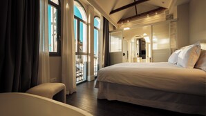 Un dormitorio amplio con una cama grande, una zona de estar y vistas al exterior a través de un ventanal.