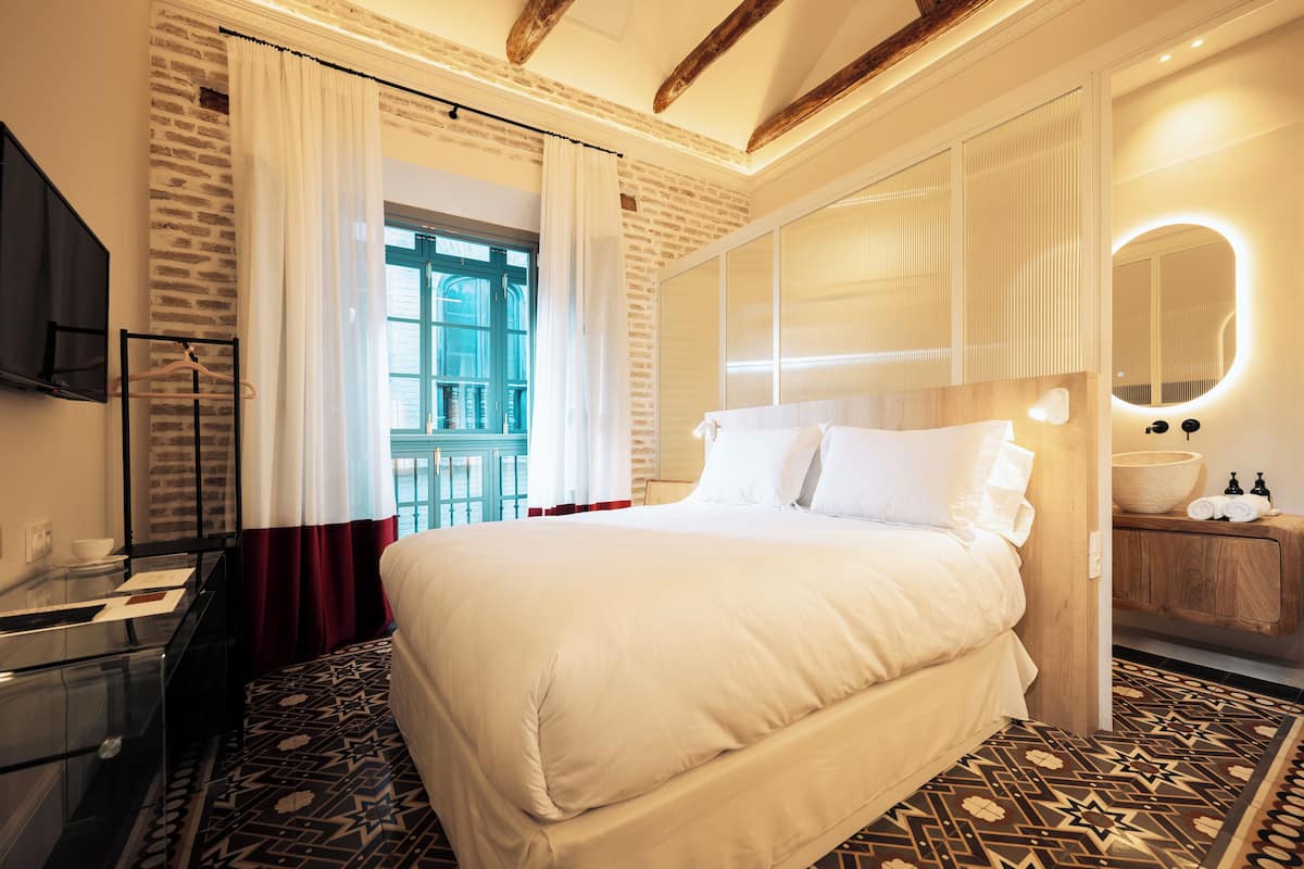 A hotel room with a large bed, a wooden dresser, a mirror, and a TV.