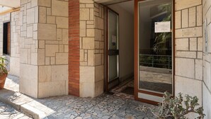 L'ingresso di un edificio con facciata in pietra, una porta in vetro e una piccola pianta in vaso.
