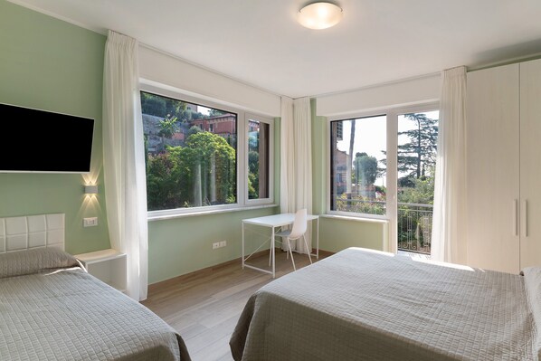 A room with two beds, a desk, and a TV.
