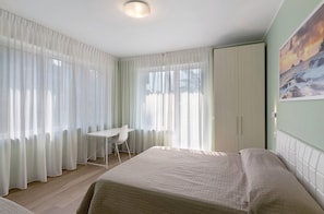A hotel room with a bed, a desk, a chair, and a wardrobe.