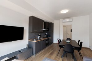 Una cocina moderna con armarios oscuros, encimera de madera y horno empotrado.