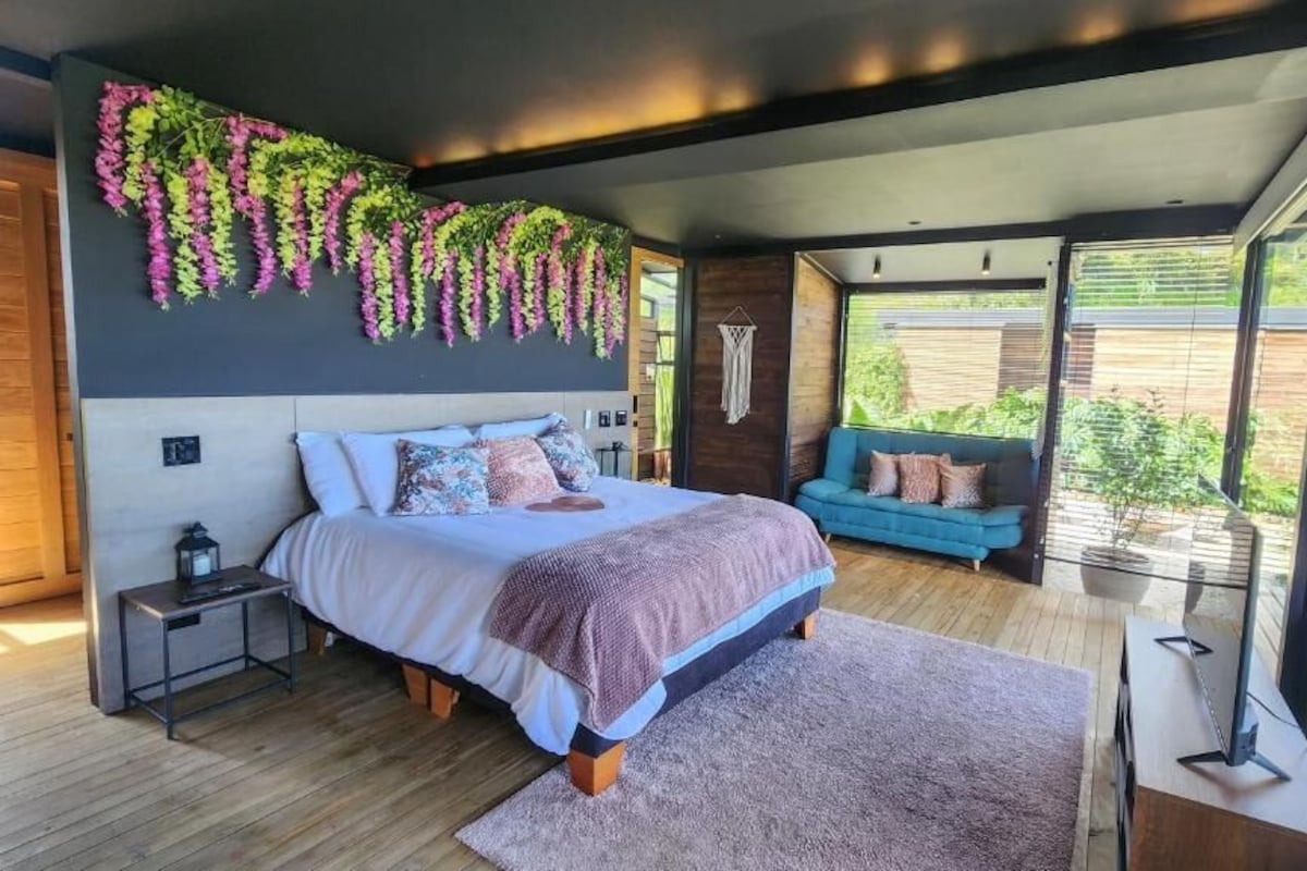A modern bedroom with a large bed, a blue sofa, and a view of the outdoors.
