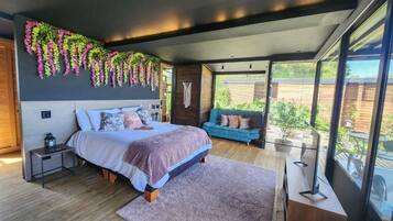 Un dormitorio moderno con una cama grande, un sofá azul y vistas al exterior.