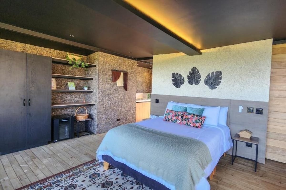 A modern bedroom with a large bed, built-in shelving, and a decorative wall piece.