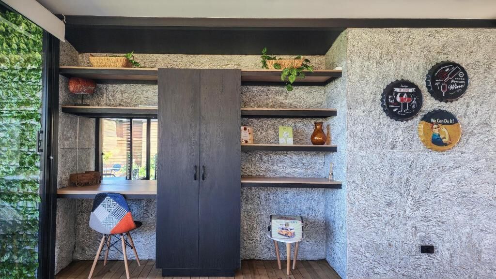 A modern kitchen with a dark wooden cabinet, open shelving with decorative items, and a small stool.