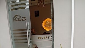 A hotel entrance with a reception desk, a glass door with a logo, and a potted plant. - KSB HOTEL (Mwanza)
