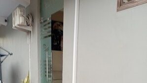 A hallway with a tiled floor, potted plants, a handrail, and a door with a poster. - KSB HOTEL (Mwanza)