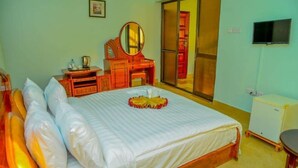 A bedroom with a bed, a dresser, a mirror, a television, and a sliding door. - KSB HOTEL (Mwanza)