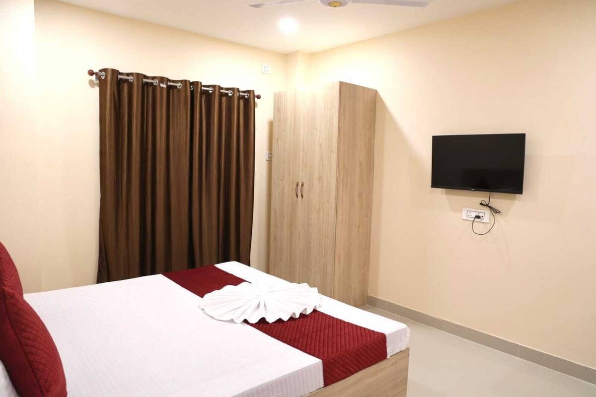 A hotel room with a bed, a wardrobe, a television, and a ceiling fan.