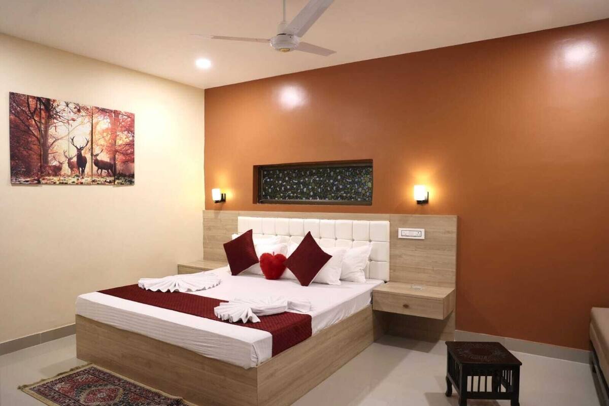 A bedroom with a large bed, a nightstand, a small table, and a ceiling fan.