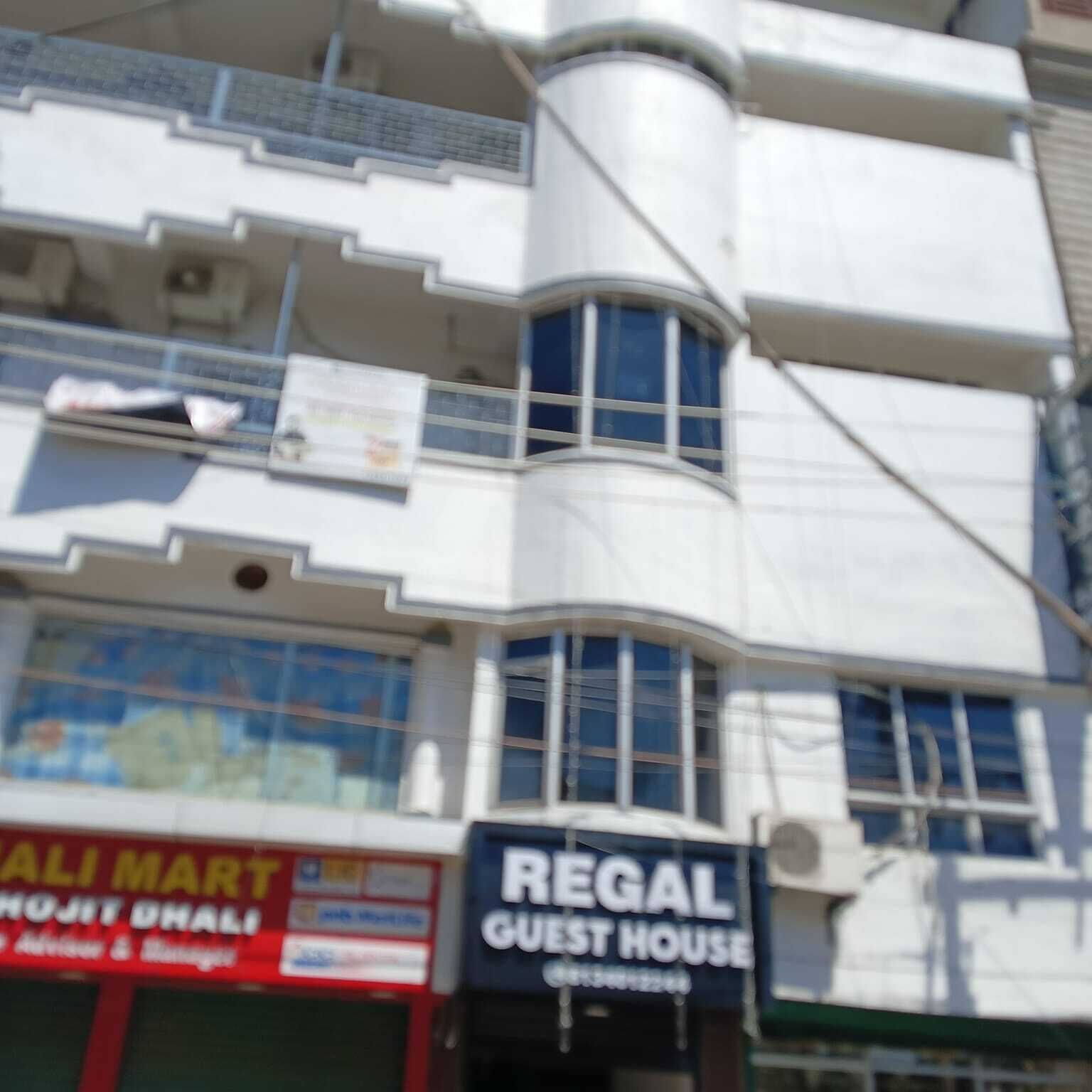 Un edificio de varios pisos con un letrero que dice "Regal Guest House" en la planta baja.