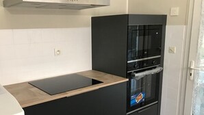 A compact kitchen with a black countertop, a built-in oven, and a stainless steel range hood. - Villa with air-conditioned areas, close to the sea, the forest, the village, and the harbor. (La Tremblade)
