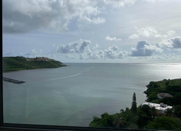 Une vue sur la côte, avec une mer calme, une petite péninsule parsemée de bâtiments et un ciel nuageux.