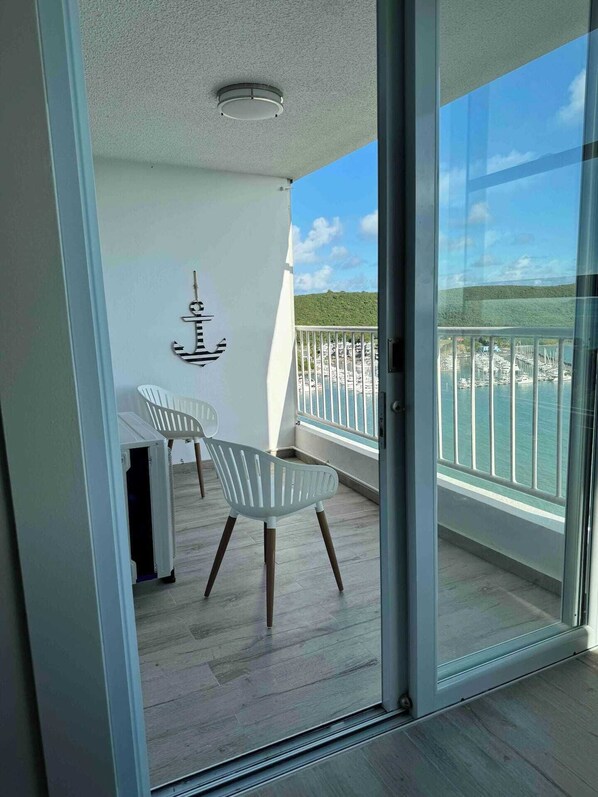 Un balcon donnant sur une marina, avec une chaise blanche.