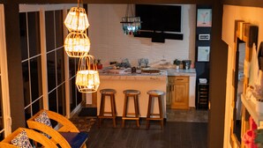 Una cocina moderna con barra, taburetes de madera y una lámpara colgante.
