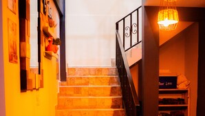 Una escalera de madera con barandilla negra que conduce a una zona de descanso con un estante y una cesta.