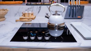 Una cocina moderna con estufa a gas, hervidor y bloque de cuchillos.
