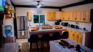 Una cocina moderna con armarios de madera, una isla central con taburetes de bar, un refrigerador, un microondas y una cafetera.
