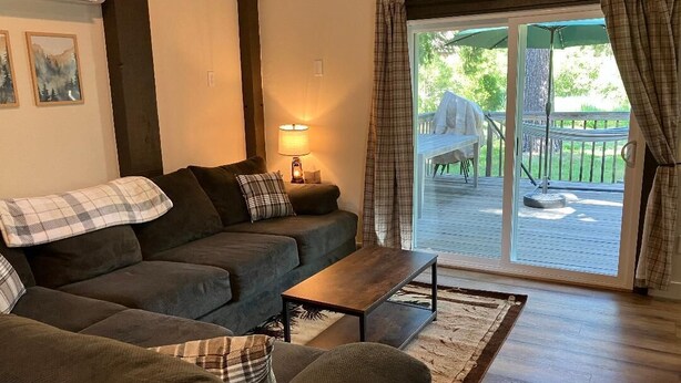 En hyggelig stue med en sofa, et sofabord og en lampe. Der er en skydedør af glas, der fører ud til en terrasse.