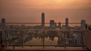 A cityscape at sunset with high-rise buildings and a body of water in the foreground. - Altair Luxury Colombo by Miracle apartment,fitness room in enchanting Colombo (Colombo)