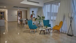 A spacious living area with teal and mustard chairs, a coffee table, and a potted plant. - Altair Luxury Colombo by Miracle apartment,fitness room in enchanting Colombo (Colombo)