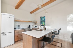 Eine moderne Küche mit einem weißen Kühlschrank, Holzschränken, einer Marmorarbeitsplatte und einem eingebauten Ofen.