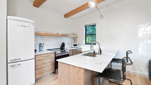 Una cocina moderna con refrigerador, estufa, microondas y alacenas de madera.