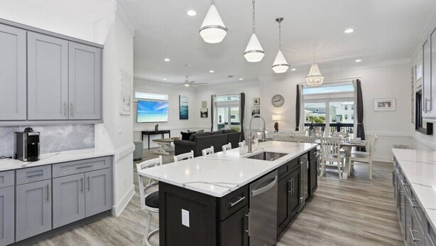 A modern kitchen with grey cabinets, a central island, and pendant lighting. - Sea Turtle Shanty, Navarre Beach (Navarre)