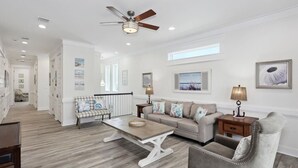 A spacious living room with a high ceiling, a ceiling fan, and a large window. - Sea Turtle Shanty, Navarre Beach (Navarre)