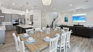 A modern kitchen with grey cabinets, a wooden dining table set for six, and a chandelier. - Sea Turtle Shanty, Navarre Beach (Navarre)