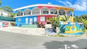 A colorful building with a central entrance, multiple balconies, and a sign indicating 'Apartments on the Mountain'. - Nature Escape Solar Energy Close to Port (Ceiba)