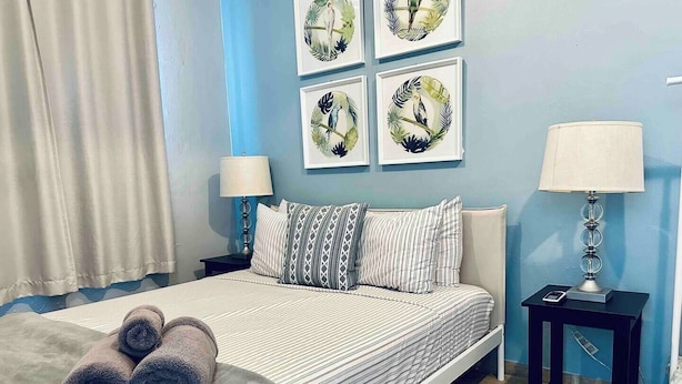A neatly made bed with striped bedding, two bedside lamps, and a set of rolled towels on the bed. - Nature Escape Solar Energy Close to Port (Ceiba)