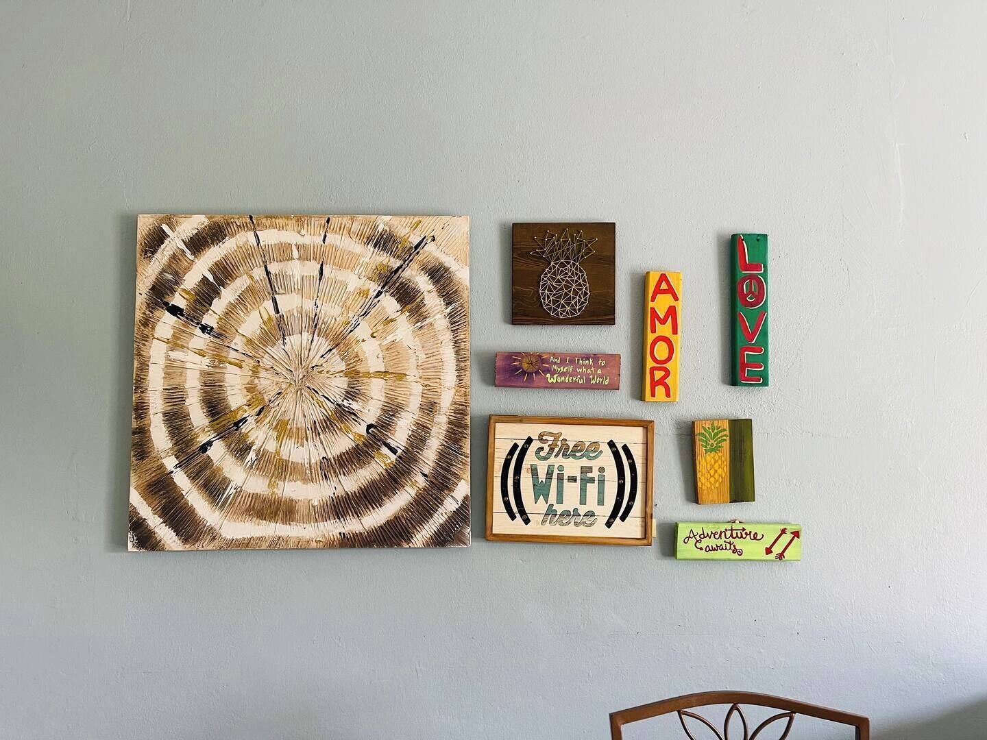 A wall with various decorative items including a circular wooden piece, a pineapple design, and several signs with words like "AMOR," "LOVE," and "Free Wi-Fi."