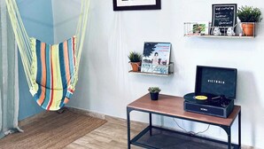 A room with a hammock, a framed picture, a shelf with plants, a small table with a record player, and a chalkboard sign. - Nature Escape Solar Energy Close to Port (Ceiba)