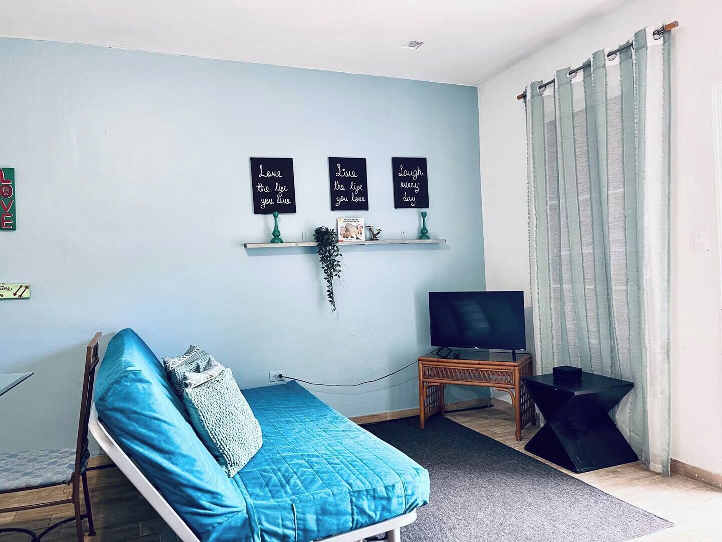 A bedroom with a bed, a television, and a shelf with motivational signs.