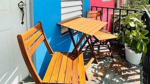 A wooden table and chairs on a balcony with a blue wall and a potted plant. - Nature Escape Solar Energy Close to Port (Ceiba)
