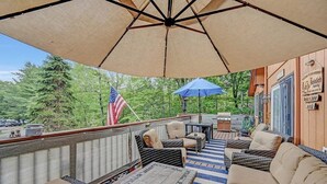 An outdoor patio with wicker furniture, a flag, and a blue umbrella.