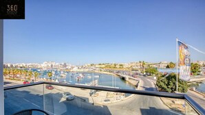 Un balcon offrant une vue sur un port de plaisance, le paysage urbain et un pont.