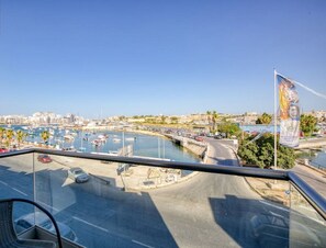 Un balcon offrant une vue sur un port de plaisance, le paysage urbain et un pont.