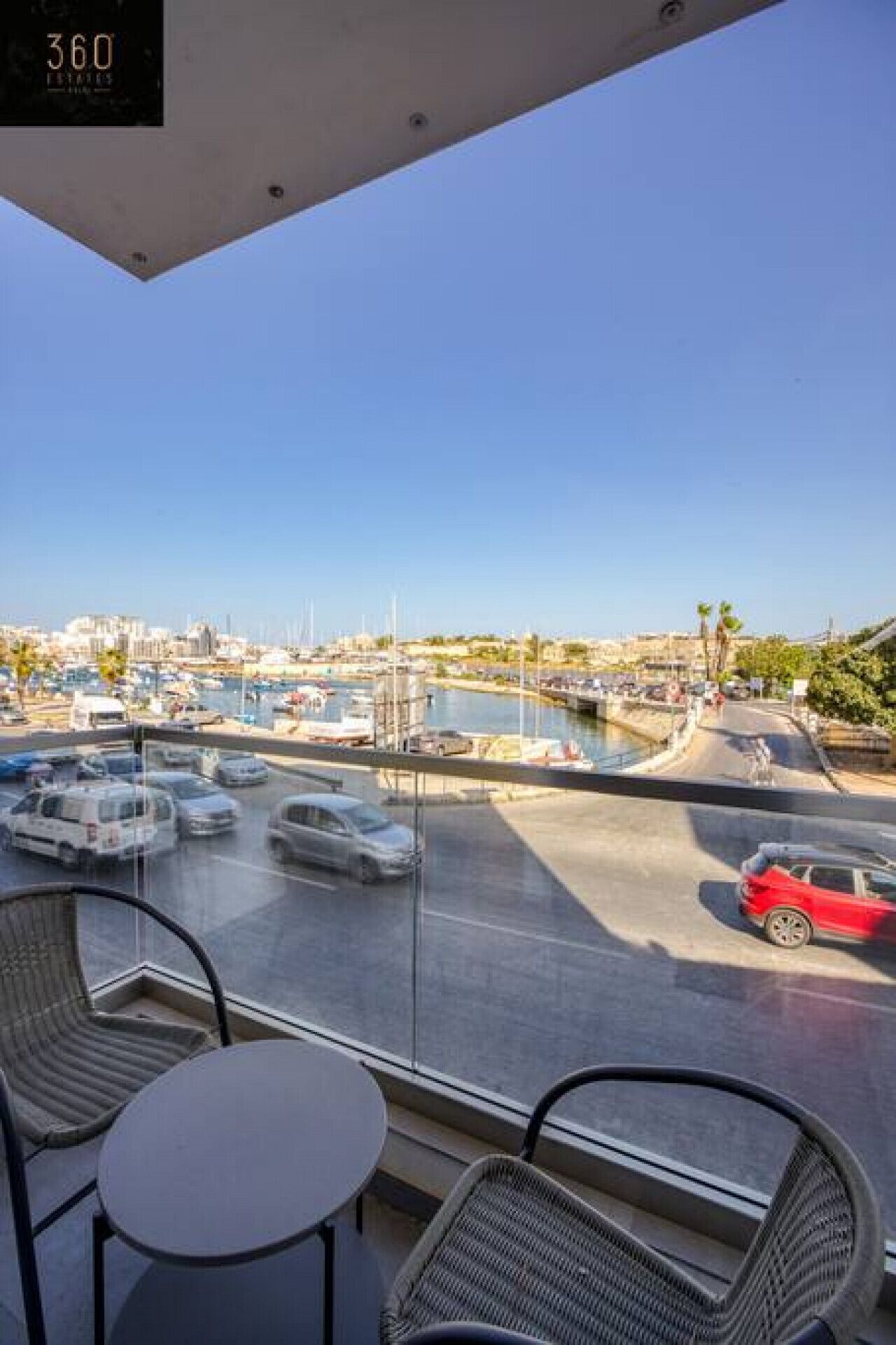 Un balcón con vistas a un puerto deportivo y al paisaje urbano.
