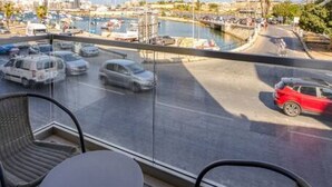 Un balcón con vistas a un puerto deportivo y al paisaje urbano.