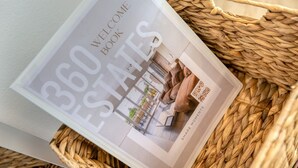 A book titled "Welcome Book Estates" with a QR code, placed on a woven basket.