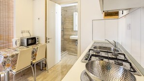 A modern kitchen with a gas stove, microwave, and a dining area with a table and chairs.