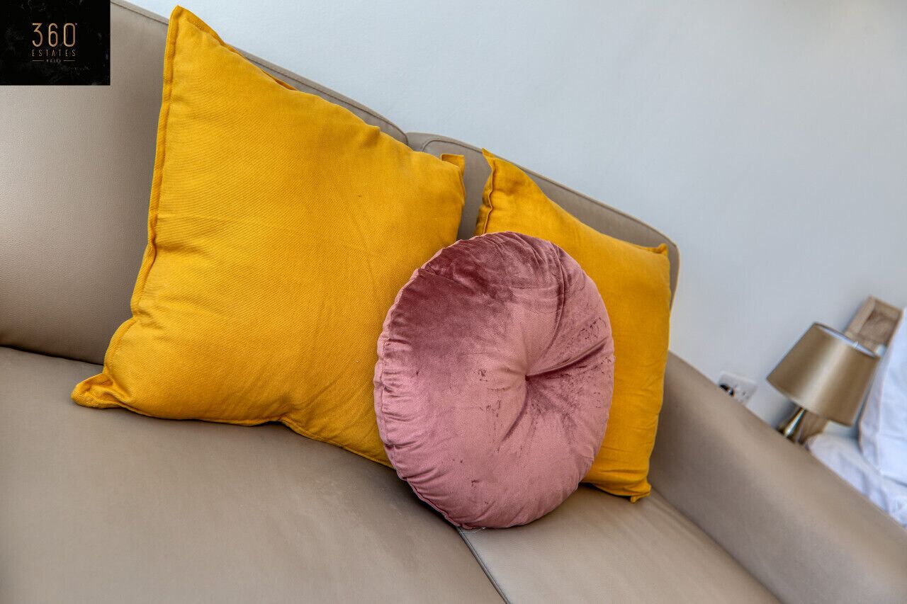Un canapé beige avec deux coussins, un jaune et un rose.