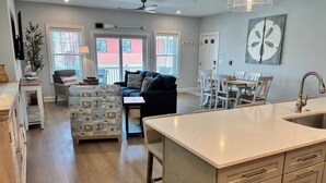 Una cocina moderna con una isla grande, suelo de madera y un comedor con mesa y sillas blancas.