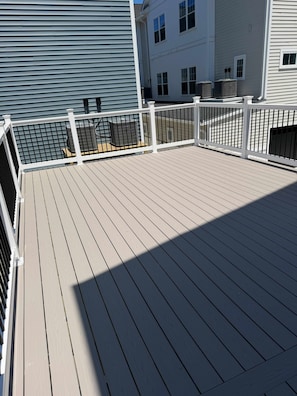 Une terrasse avec une rambarde blanche, des unités de climatisation et un bùtiment en arriÚre-plan.