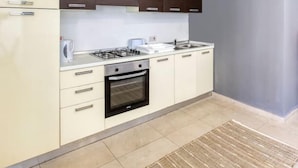 A compact kitchen with a stove, oven, and sink, featuring light-colored cabinets and a dark countertop. - Spacious, comfortable 2BR home in Msida with WIFI (L-Imsida)