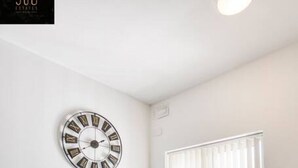 A modern meeting room with a glass table, black chairs, a wall clock, and a window with blinds. - Spacious, comfortable 2BR home in Msida with WIFI (L-Imsida)