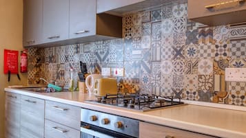 Una cucina con piastrelle decorate, un fornello a gas, un tostapane e un estintore.